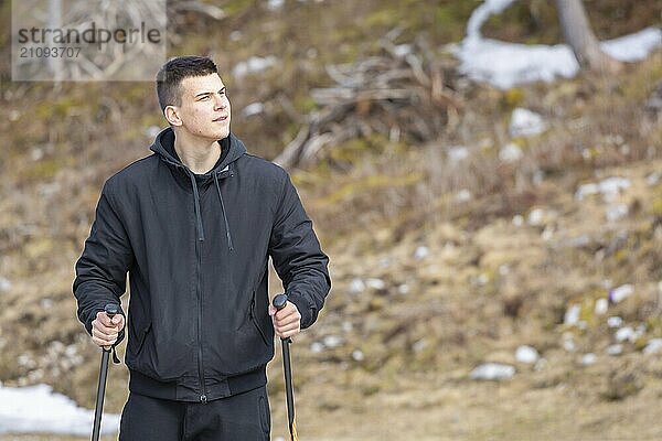 Lässiger und aktiver gesunder Mann beim Wandern in den alpinen Bergen mit Trekkingstöcken