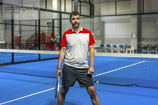 Porträt eines sportlichen erwachsenen kaukasischen Mannes auf einem Paddle Tennisplatz