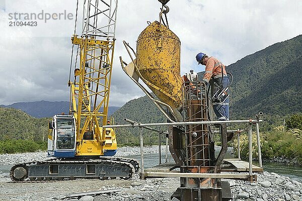 Builders construct a concrete bridge over a small river in Westland  New Zealand  Oceania