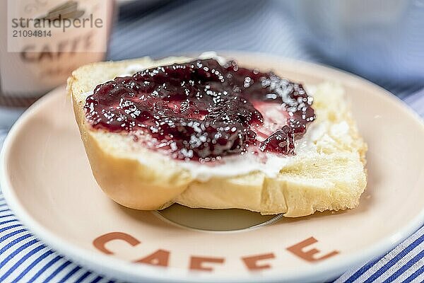 Mini Butter Brioche mit Marmelade und Kaffeebecher auf hellblauem Hintergrund