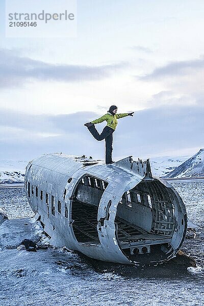 Frau auf dem Gipfel des Solheimasandur Flugzeugs beim Meditations Yoga in Island im Winter