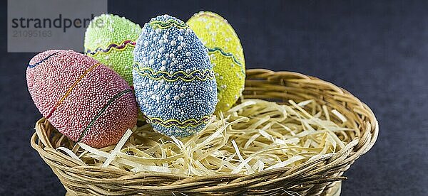 Ostern farbige Eier in einem Korb vor einem trendigen schwarzen Hintergrund. Minimale Ostern Konzept. Osterkarte mit Kopierraum für Text