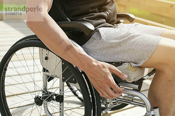 Behinderter junger sportlicher Mann im Rollstuhl  der mit der Hand die Räder hält und dreht  treibt Sport