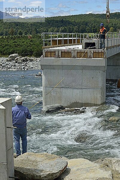 Builders construct a concrete bridge over a small river in Westland  New Zealand  Oceania