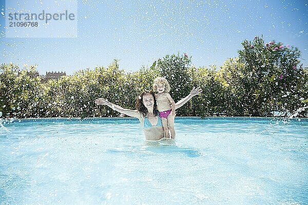 Glückliche Familie spielt im blauen Wasser des Swimmingpools in einem tropischen Resort am Meer. Sommerferien Konzept