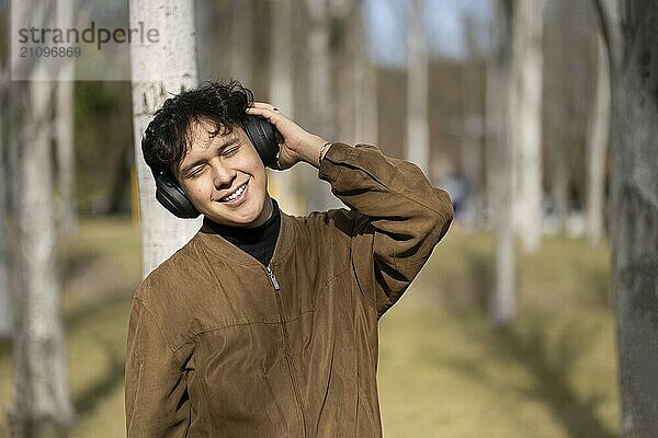 Young latin man listening to music outdoors with headphones. Expression of happiness