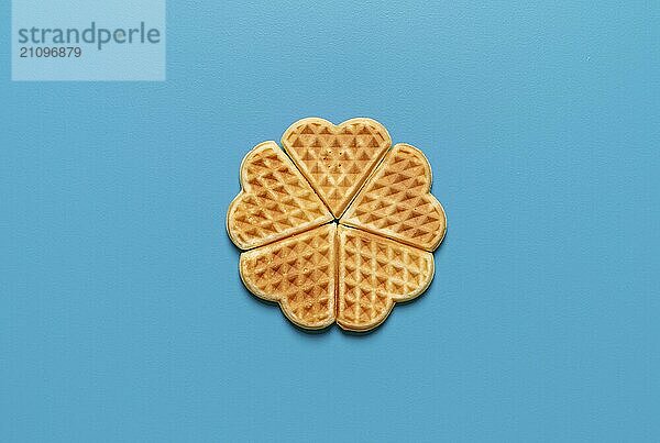 Draufsicht mit herzförmigen Waffeln minimalistisch auf einem blauen Hintergrund