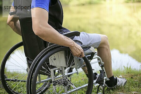 Glücklicher junger behinderter Mann in einem Rollstuhl sitzend in der Natur