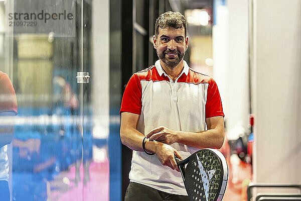 Smiling mature man playing with paddle tennis racket in an indoor court