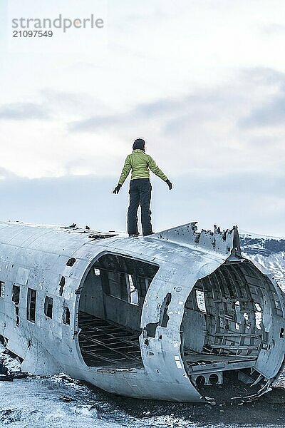 Frau auf dem Dach des Solheimasandur Flugzeugs mit geöffneten Armen in Meditation in Island