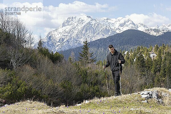 Lässiger und aktiver gesunder Mann beim Wandern in den alpinen Bergen mit Trekkingstöcken