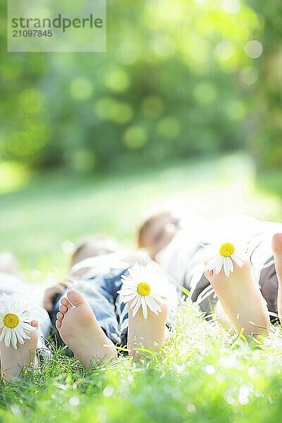 Glückliche Familie liegt auf grünem Gras im Freien im Frühling Park