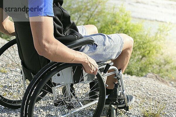 Happy young man in wheelchair outside in nature on a sunny summer day