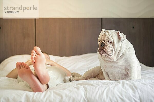 Schöne Frau schläft im Bett mit englischer Bulldogge Welpe. Nur die Füße