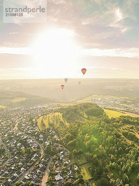 Heißluftballons schweben über eine Stadt und bewaldete Hügel bei Sonnenuntergang  Calw  Schwarzwald  Deutschland  Europa