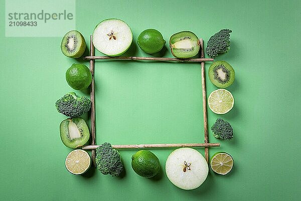 Blick von oben auf grünes Obst und Gemüse in einem quadratischen Rahmen aus Bambusstäben  auf grünem Hintergrund. Vegetarisches Essen. Entgiftung Kontext