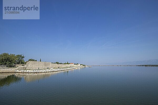 Skyline einer kleinen Mittelmeerstadt  historisches Stadtzentrum mit massiven Stadtmauern auf einer Insel in einer Bucht oder Lagune. Morgenstimmung in Nin  Zadar  Dalmatien  Kroatien  Adria  Europa