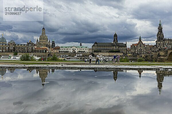 Die Dresdner Silhouette mit dunklen Wolken hinter der Frauenkirche  spiegelt sich am Elberadweg in einer Pfütze.  Elberadweg  Dresden  Sachsen  Deutschland  Europa