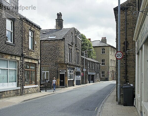 Mytholmroyd  west yorkshire  united kingdom  13 july 2019: a woman walking past shops and houses on new road in mytholmroyd west Yorkshire