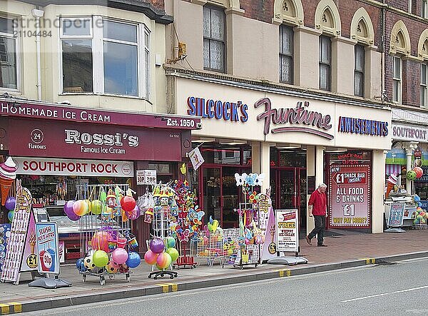 Southport  merseyside  united kingdom  28 june 2019: a shop in neville street in southport merseyside selling ice cream rock beach toys and snacks with a man walking out of an amusement arcade