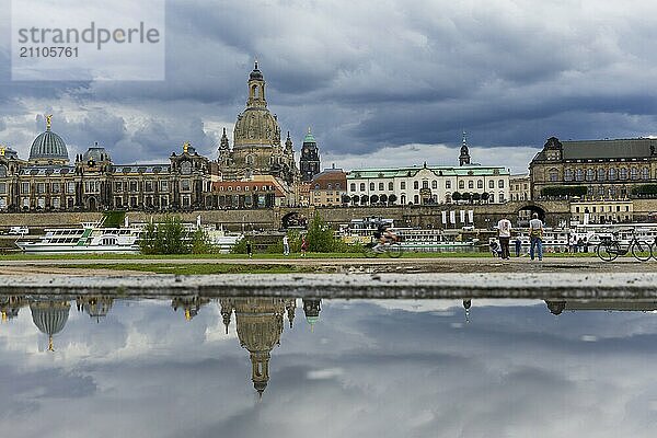 Die Dresdner Silhouette mit dunklen Wolken hinter der Frauenkirche  spiegelt sich am Elberadweg in einer Pfütze.  Elberadweg  Dresden  Sachsen  Deutschland  Europa