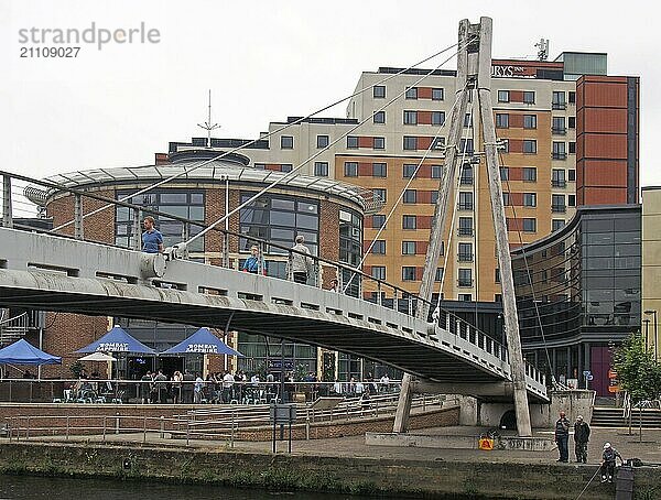 Leeds  west yorkshire  vereinigtes königreich  4. juli 2019: Die Millennium Fußgängerbrücke in Leeds mit Menschen  die nach der Arbeit an einer Bar im Freien trinken  und Männern  die im Fluss angeln