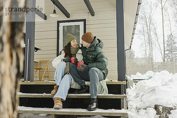 Romantic couple in warm clothes sitting together on porch