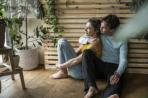 Thoughtful young man embracing girlfriend sitting at home