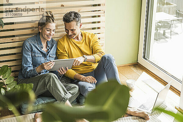 Couple sitting together on mattress using digital tablet