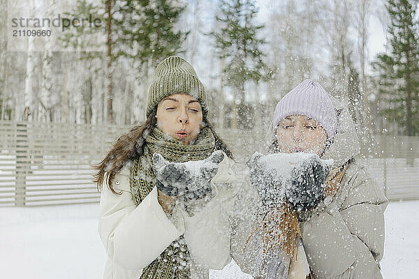 Friends in warm clothes blowing snow