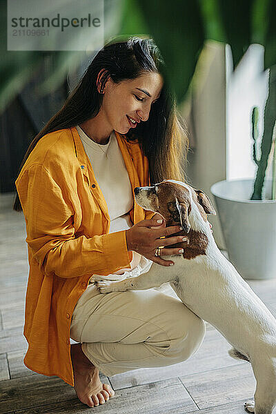 Pregnant woman petting dog at home