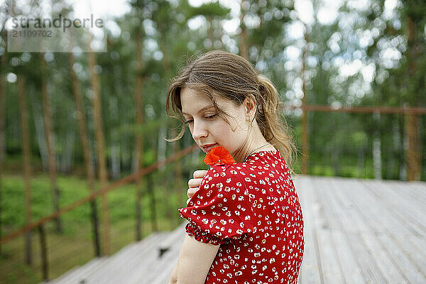 Woman with brown hair holding red flower