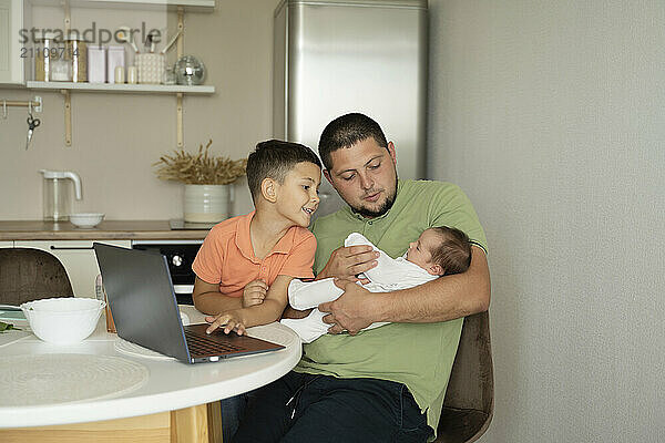 Playful father with children sitting in kitchen