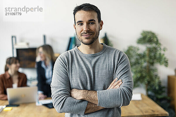 Smiling businessman with arms crossed in office