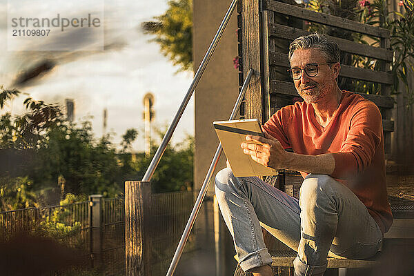 Man using tablet PC sitting on steps