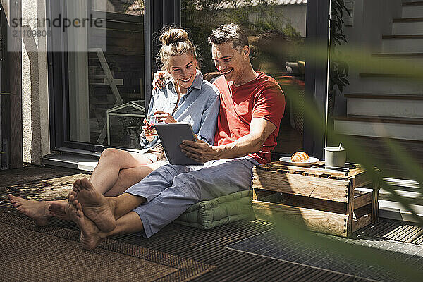 Couple relaxing on balcony with digital tablet