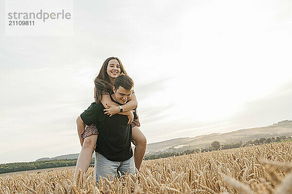 Man piggybacking girlfriend in spikelet field