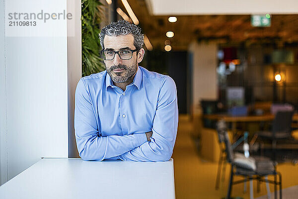 Businessman with arms crossed standing at co working space