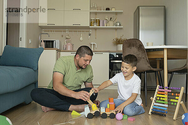 Happy boy with father sitting on floor and playing at home