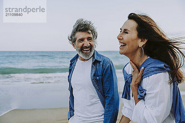 Cheerful senior couple walking by sea at beach