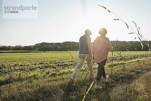 Senior couple walking near field on sunny day