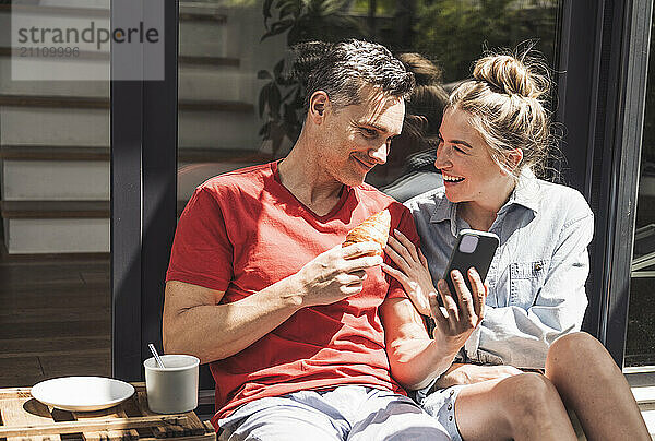 Couple relaxing on balcony with smart phone