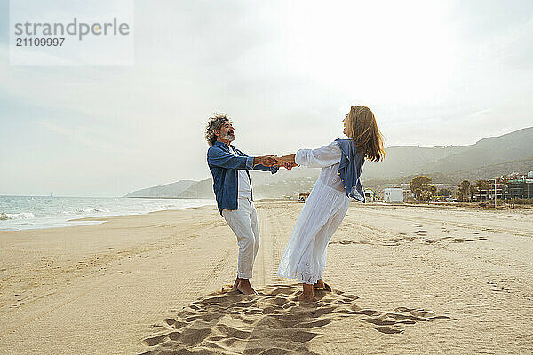 Happy senior couple holding hands and standing together at beach