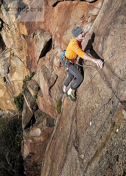 Man holding rope and climbing on rock mountain