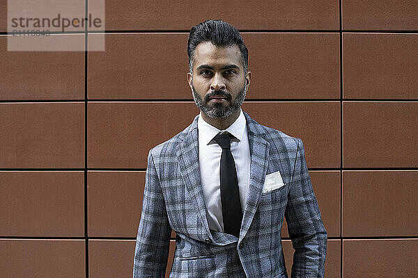 Businessman in suit near brown wall