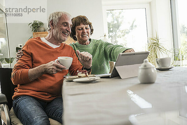 Smiling senior couple using digital PC at home