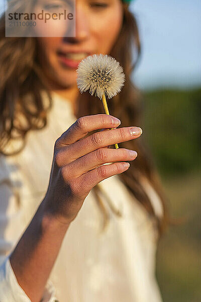 Young woman holding dandelion flower