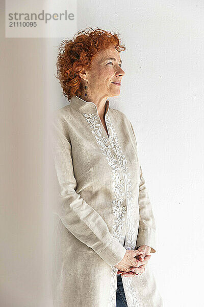 Thoughtful woman standing in front of white wall