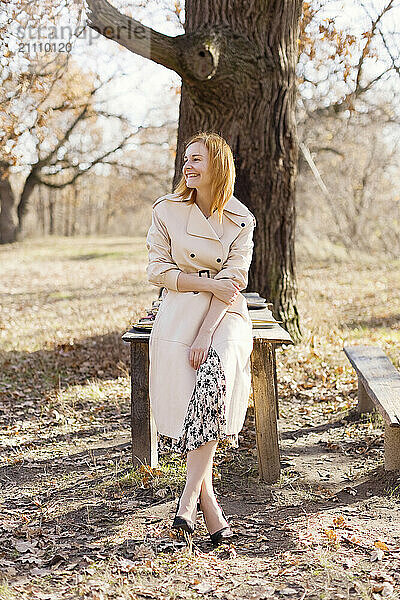 Smiling woman in trench coat at forest