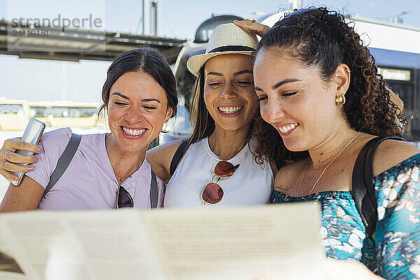 Happy female friends looking at map